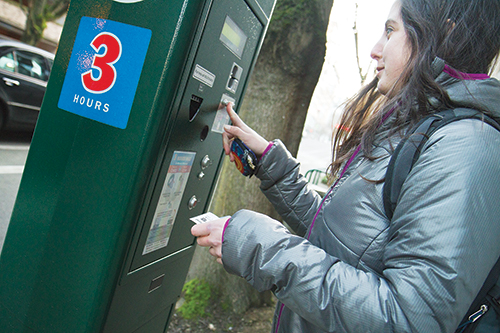 Belinda Judelman, a first-year graduate urban planning student, feeds the parking meter on her way to class. After Feb. 7, many parking fines will see an increase throughout Portland. Photo by Kayla Nguyen.