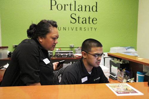 Kanani Martinez, coordinator of the campus visit program, and Nicholas Keahi Ho, a student assistant and senior community development major, discuss work in the Orientation and Campus Visits Office. Photo by Kayla Nguyen.