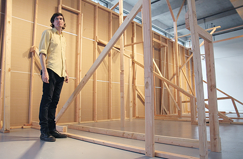 PSU art student Leif Anderson stands next to his graduate art exhibition, “Window Room,” which is on display in the Autzen Gallery. Photo by Kayla Nguyen.