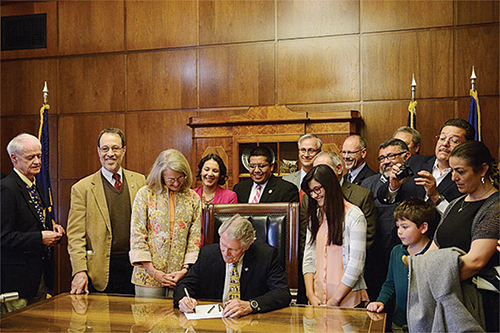Governor Kitzhaber, surrounded by supporters of tuition equity, signs the bill into law. Students who can’t prove citizenship can now pay in-state tuition at Oregon’s public universities. Photo © AP photo/statesman journal, Danielle Peterson